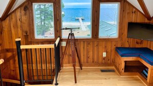 A room with wooden walls and a sloped ceiling, large windows offering a view of the sea, a telescope, and a bench. - All Year Retreat - Indoor Heated Pool, Beach, Game & Movie Cottage, Sleeps 21 (Hague)
