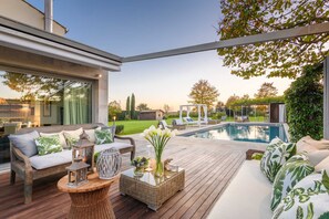 An outdoor deck with a pool, furnished with sofas and a table, surrounded by greenery. - Villa Campanile Farmhouse (Castelfranco di Sotto)