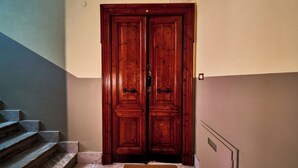 A wooden double door with a doormat that reads "Welcome."