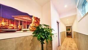 A hotel lobby with a large poster of a historical building, a potted plant, and a wooden floor.