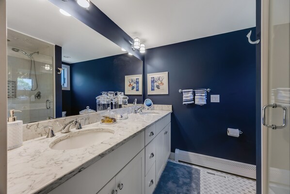 A modern bathroom with two sinks, a large mirror, and dark blue walls.