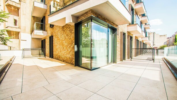 A modern building with a glass entrance, a brick facade, and a tiled ground. - Central Carol ApartHotel 1 (Bucharest)