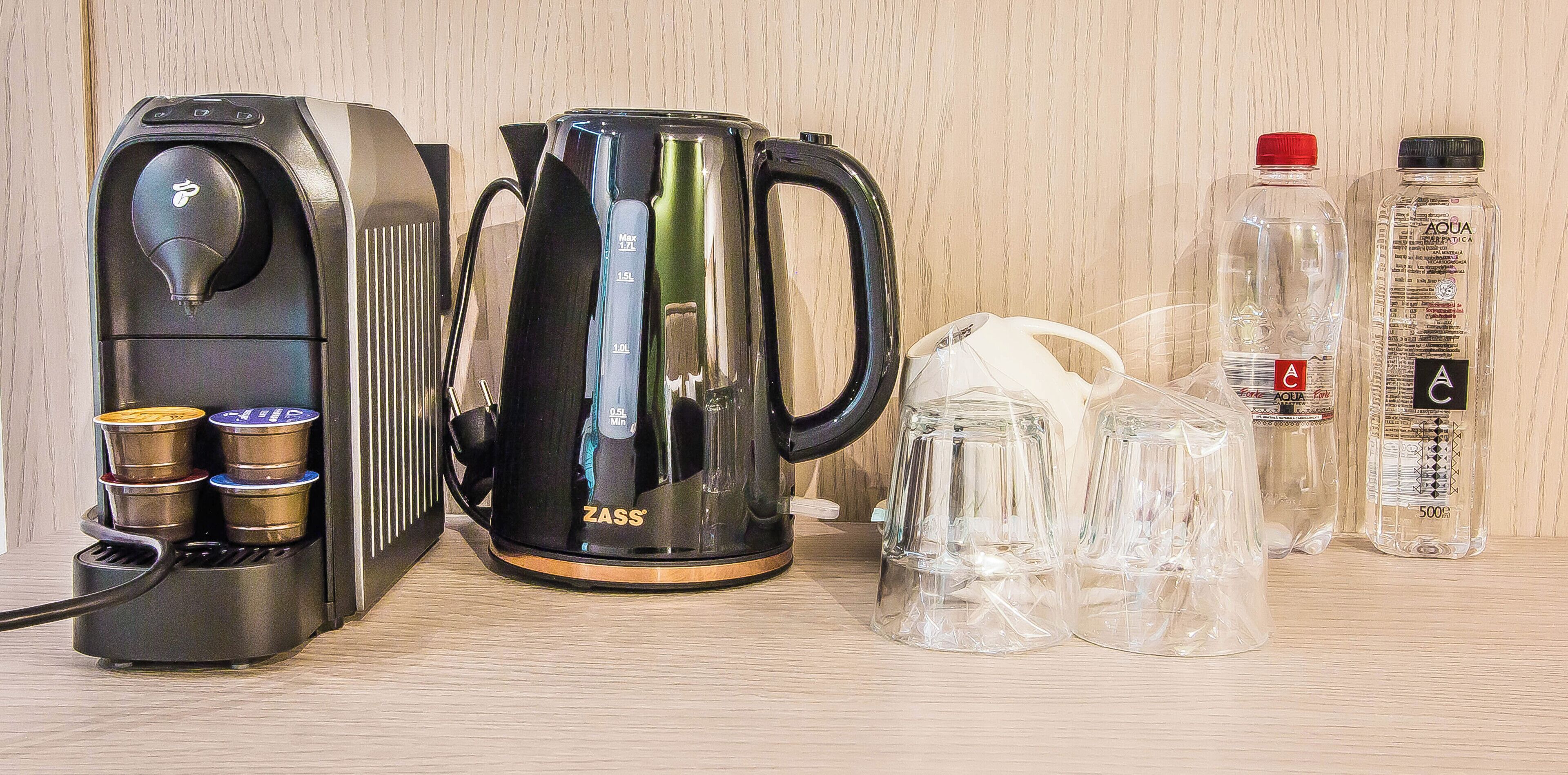 Una cafetera, un hervidor y dos botellas de agua sobre una superficie de madera.