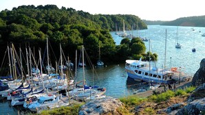 A marina with multiple sailboats docked, surrounded by lush greenery and rocky terrain. - Maison de Campagne au Calme, for lovers of nature and beautiful walks (La Chapelle-de-Brain)