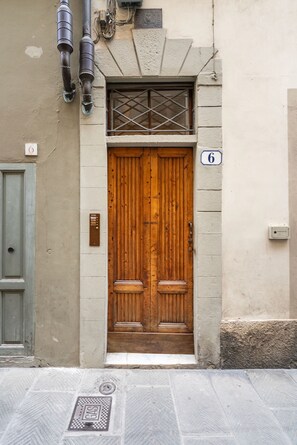 A wooden double door with a small window above it, a number '6' sign, and a manhole cover on the ground. - La Casa di Angelique - Florence Dolce Vita (Florence)