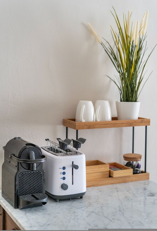 Una cocina con un panel para hacer pan, una tostadora y una planta en maceta sobre una estantería.