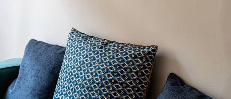 A wooden sign with the letters "XS" mounted on a wall above a sofa with patterned cushions.