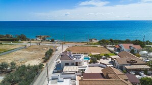 A coastal residential area with houses, a road, and a view of the sea.