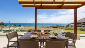 A dining table set for four with a view of the sea.