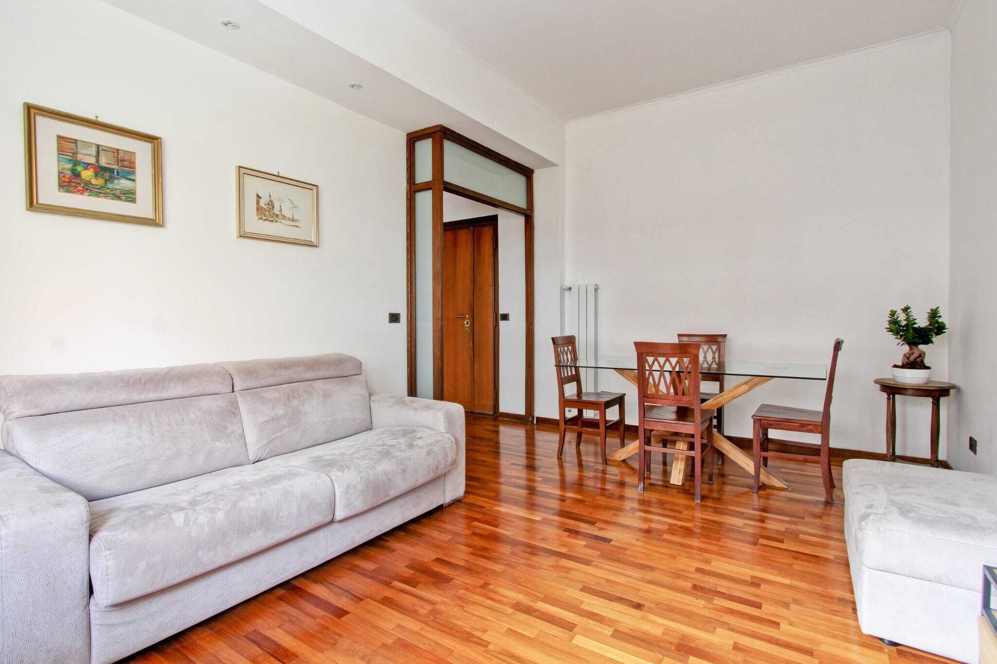 Un salon comprenant un canapé, une table à manger avec des chaises et une petite table d’appoint sur laquelle est posée une plante.