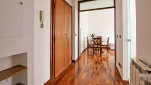 A hallway with wooden flooring, a wooden door, and a dining area with a table and chairs. - Quiet and charming house near Trastevere (Roma)