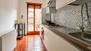 A narrow kitchen with a tiled backsplash, a stainless steel sink, and a gas stove. - Quiet and charming house near Trastevere (Roma)