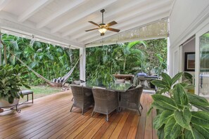 A covered patio with a glass table and wicker chairs, surrounded by lush greenery and a hammock. - Private Family Villa at Casa de Campo (La Romana)