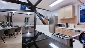 A modern kitchen with a dining area, featuring a black countertop, stainless steel appliances, and wooden cabinets. - Alpha Apartments: Grand Loft for 8, Roof Terrace (Krefeld)