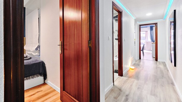 A hallway with wooden doors and a bed with a dark blanket.