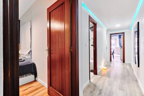 A hallway with wooden doors and a bed with a dark blanket.
