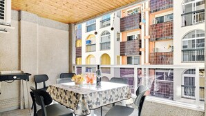 An outdoor dining area with a table and chairs, a grill, and a view of colorful buildings.