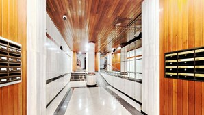 A modern hallway with wooden paneling, marble walls, and a central staircase.