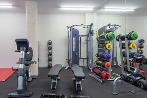 A gym with exercise equipment, benches, and weight racks. - Student Only The Barn (Exeter)