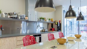 A modern kitchen with a large island, red chairs, and hanging pendant lights.
