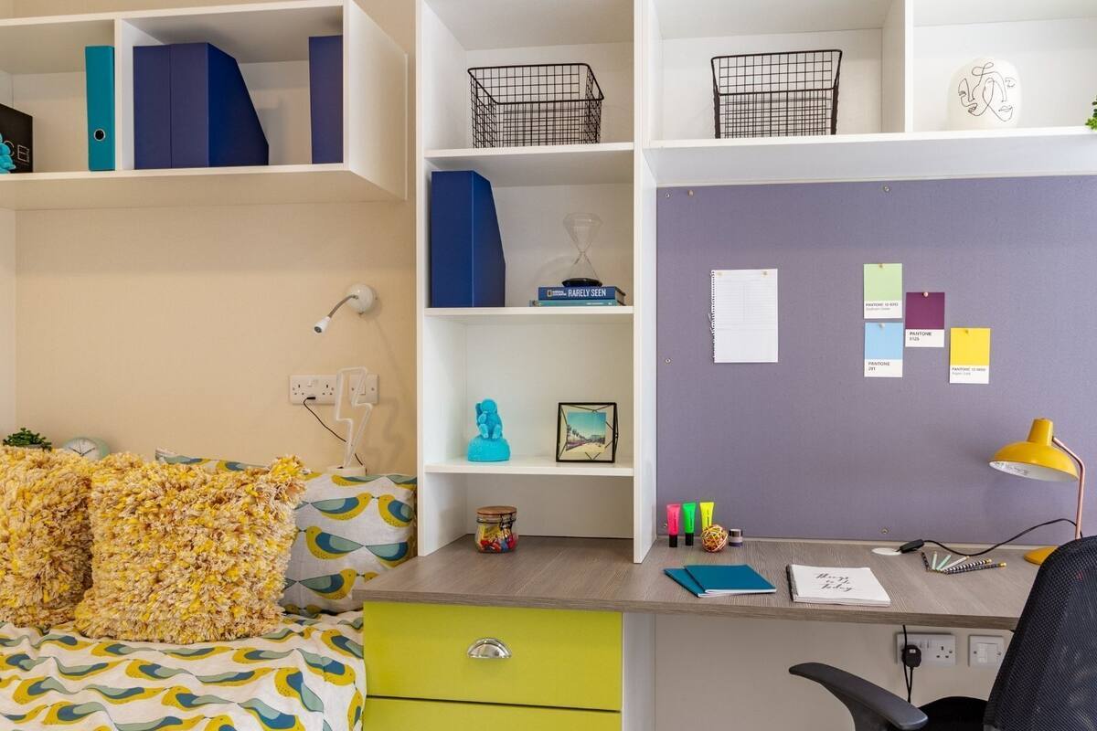 A neatly organized bedroom with a bed, a desk, and shelves.