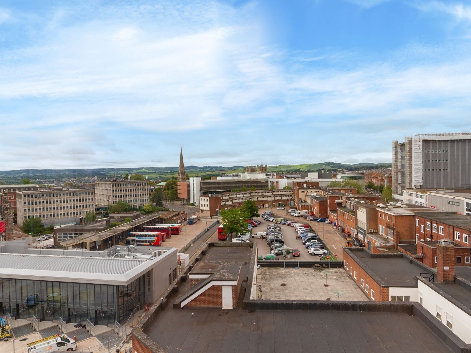 A parking area with multiple cars, a bus station, and a large building with a pointed tower.