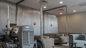 A modern living room with a vintage tractor, contemporary furniture, and a decorative wall with a geometric pattern.