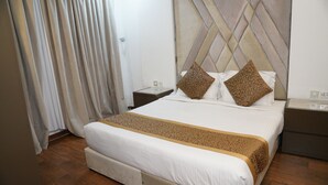 A hotel room with a large bed, a headboard with a geometric pattern, two nightstands, and a wooden floor.