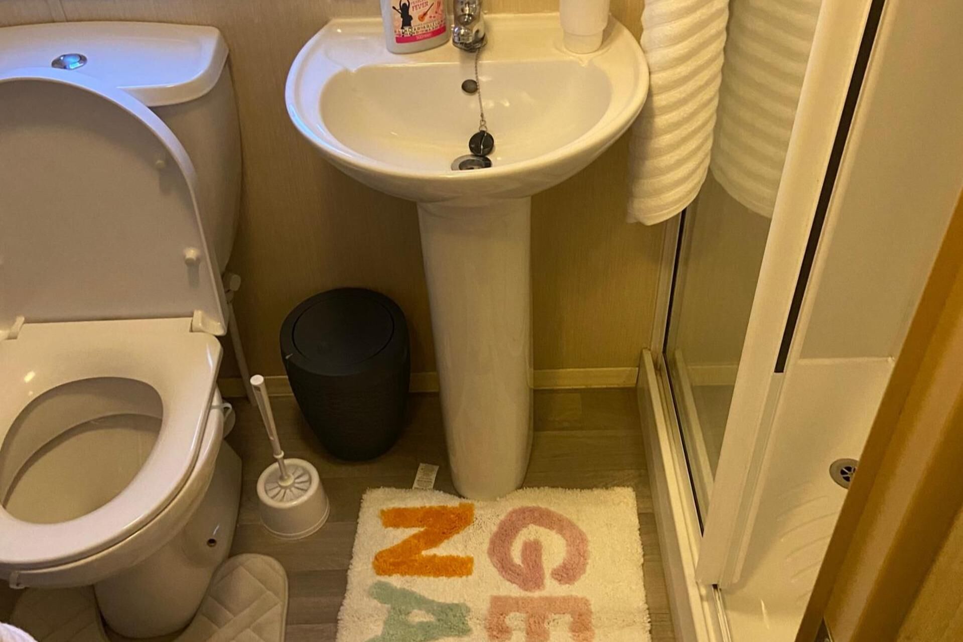 Une salle de bain équipée de toilettes, d’un lavabo et d’une poubelle.