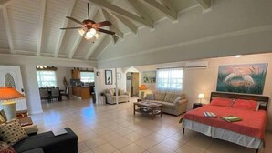A spacious living area with a high ceiling, a bed, a sofa, a coffee table, and a dining area. - Big Vacation Plex (Freeport)