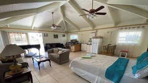 A spacious room with a large bed, a sofa, a dining table, and a kitchen area. - Big Vacation Plex (Freeport)