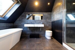 A modern bathroom with a skylight, a freestanding bathtub, a large mirror, and a glass-enclosed shower area. - Delightful 3-bed Flat with Parking  (Edinburgh)