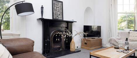 A living room with a fireplace, sofa, coffee table, and television.