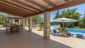 Un patio exterior con piscina, sillas de descanso y una mesa con sillas.