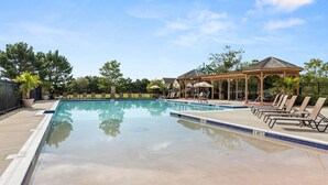Une piscine avec des chaises longues et un kiosque.