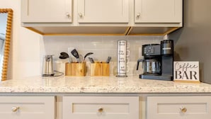 A kitchen with white cabinets, a marble countertop, a coffee maker, and a sign that reads "Coffee BAR".
