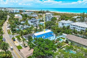 A residential area with a prominent blue building, a clear road, and a beach in the background.