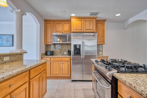 A kitchen with wooden cabinets, a stainless steel refrigerator, a microwave, a gas stove, and granite countertops. - 5 bed Home W/ Private Pool on Siesta Key! (Siesta Key)