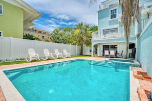 A swimming pool with white lounge chairs, a white fence, and a building with a balcony. - 5 bed Home W/ Private Pool on Siesta Key! (Siesta Key)