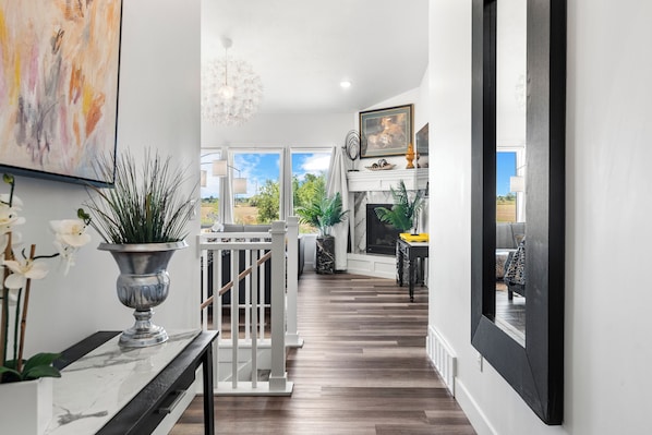 A modern interior with a wooden floor, white walls, and a staircase leading to a balcony.