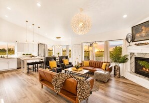 A spacious living room with a fireplace, a dining area, and a kitchen. - Luxury 6BR |Hot Tub |Private Pickleball |Sleeps 15 (West Haven)
