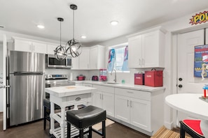A modern kitchen with white cabinets, stainless steel appliances, and a central island with stools.