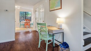 A room with a desk, chair, lamp, and a map on the wall.