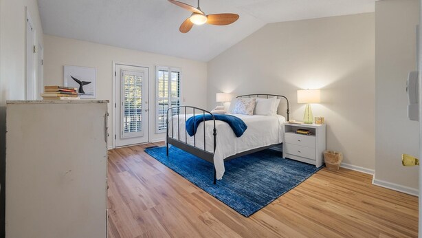 A bedroom with a bed, bedside tables, a ceiling fan, and a view through a door.