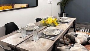 A dining table set with plates, glasses, and a centerpiece of yellow flowers. - Oak Suite - 2 Bed - Sleeps 4 - Central Blackpool (Blackpool)