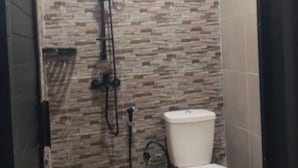 Un bagno con il water, una cabina doccia e un rivestimento in piastrelle.