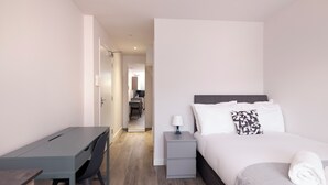A modern hotel room with a bed, bedside table, desk, and chair. - JOIVY Chic Studio near Holyrood Park (Edinburgh)