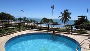 Una piscina con vista sull'oceano e palme.
