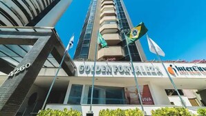 Un edificio alto con il cartello "Golden Fortuna" e bandiere, tra cui quella brasiliana.