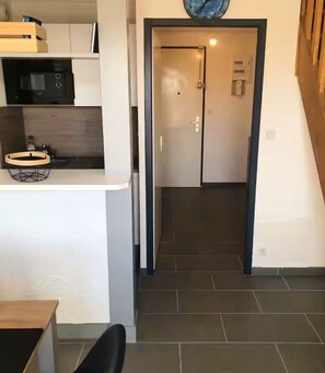 A kitchen area with a microwave, a small round table, and a cabinet.